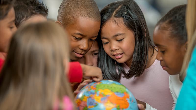 Students gathered around a globe while learning about climate awareness